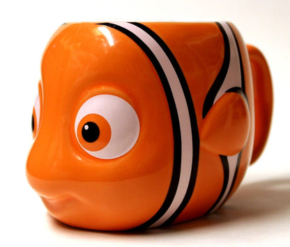 An orange fish-shaped ceramic mug designed like a clownfish, featuring white stripes and a large detailed eye, photographed on a clean white background.