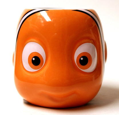 An orange fish-shaped ceramic mug or container with a cartoon face, featuring large white eyes with black pupils and a white stripe above, photographed on a white background.