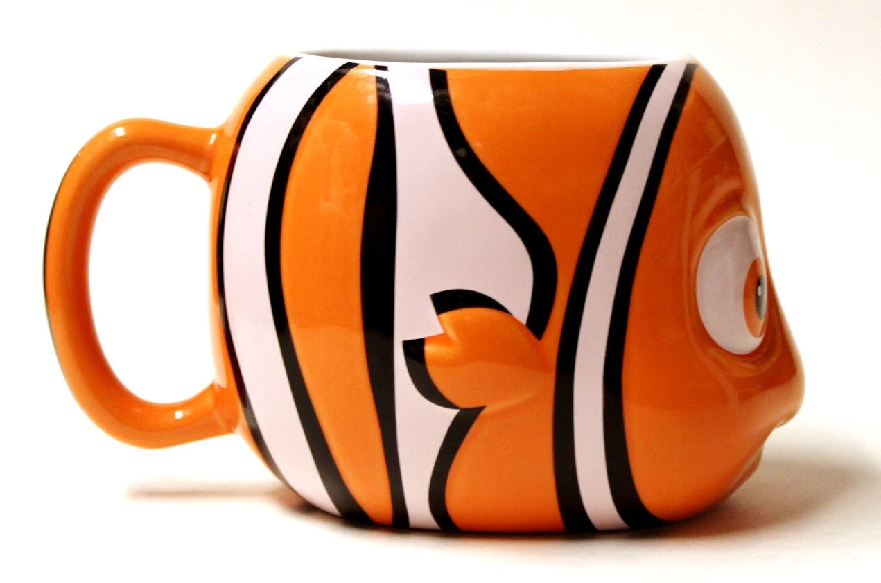 An orange ceramic mug designed to look like a clownfish, featuring bold black and white stripes and a detailed eye on the side, set against a plain white background.