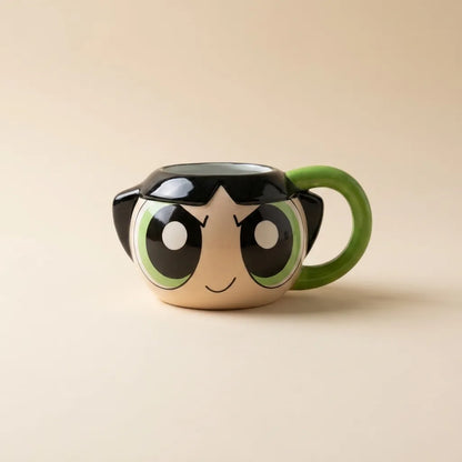 A ceramic mug shaped like the Powerpuff Girls character Bubbles, featuring her signature green handle, black hair, and large cartoon eyes on a warm beige background.