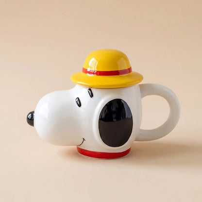 A ceramic novelty mug shaped like Snoopy wearing a yellow hat with a red band, shown on a plain beige background.