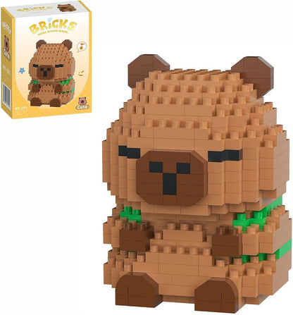 A capybara-shaped block building toy made of tan and brown bricks with small green accents, shown next to its yellow retail box on a white background.