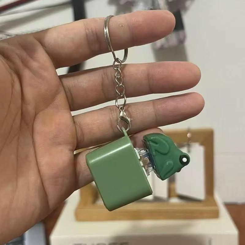 Hand holding a green keychain with a small device attached, blurred background