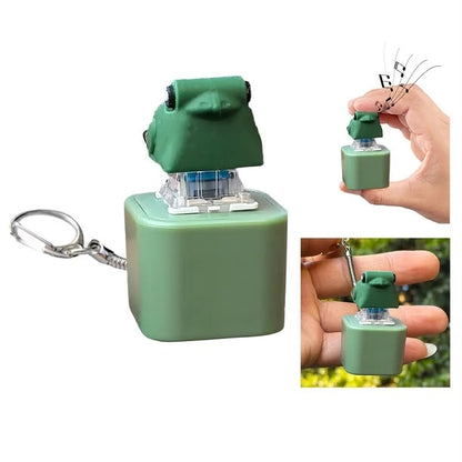 A small frog-shaped keychain alarm or novelty accessory in muted green, shown on a white background with two smaller inset photos of a hand holding it and a key ring attached.
