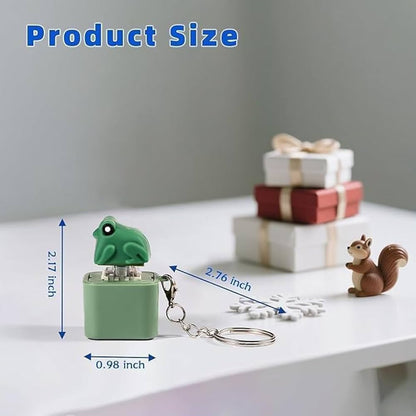 A small frog-shaped keychain in mint green is shown on a white tabletop with dimension arrows and text indicating 2.17 inches tall by 0.