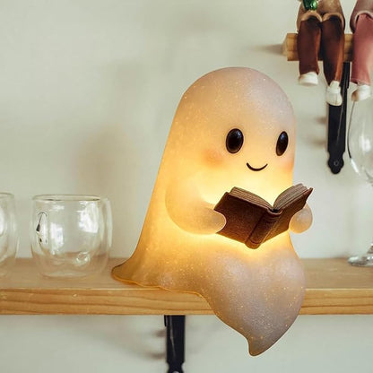 A 3D-printed silicone ghost reading lamp sitting on a shelf with a warm LED glow.