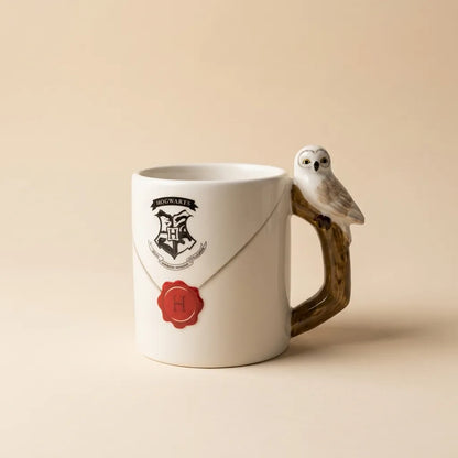 A white ceramic Harry Potter Hogwarts mug featuring a 3D owl handle perched on a branch, with a printed Hogwarts crest and red wax seal design.
