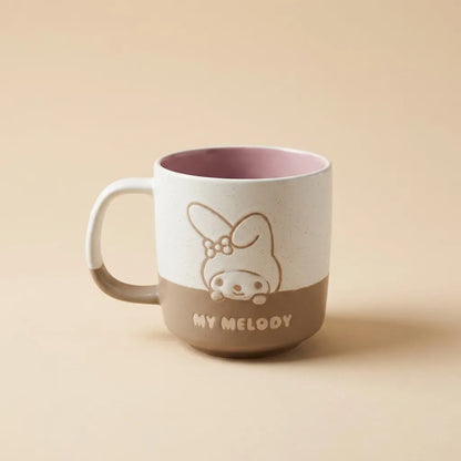 A ceramic mug with a white upper half and a brown lower half, featuring a line-art illustration of My Melody and the text 'MY MELODY' on the front. The mug has a dusty pink interior and is photographed on a solid beige background.