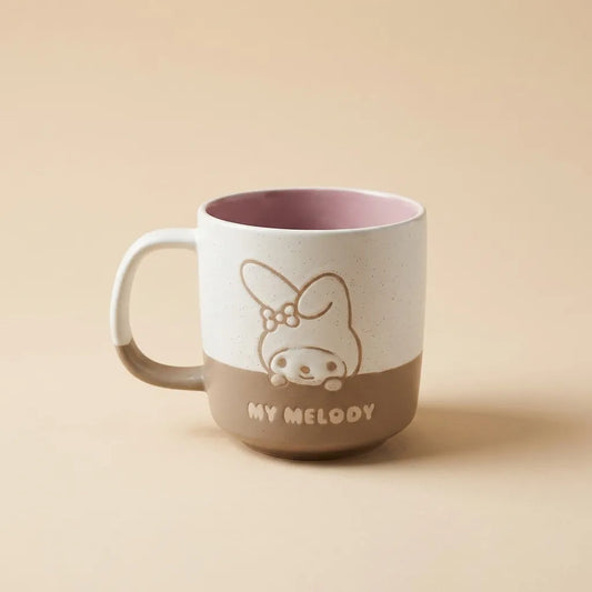 A ceramic mug with a white upper half and a brown lower half, featuring a line-art illustration of My Melody and the text 'MY MELODY' on the front. The mug has a dusty pink interior and is photographed on a solid beige background.