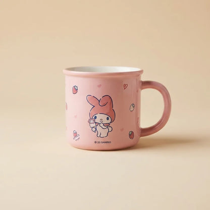 A pink ceramic mug featuring a cute cartoon bunny character holding a flower, with small strawberry and heart motifs. The mug has a white interior and a pink handle, set against a solid beige background.