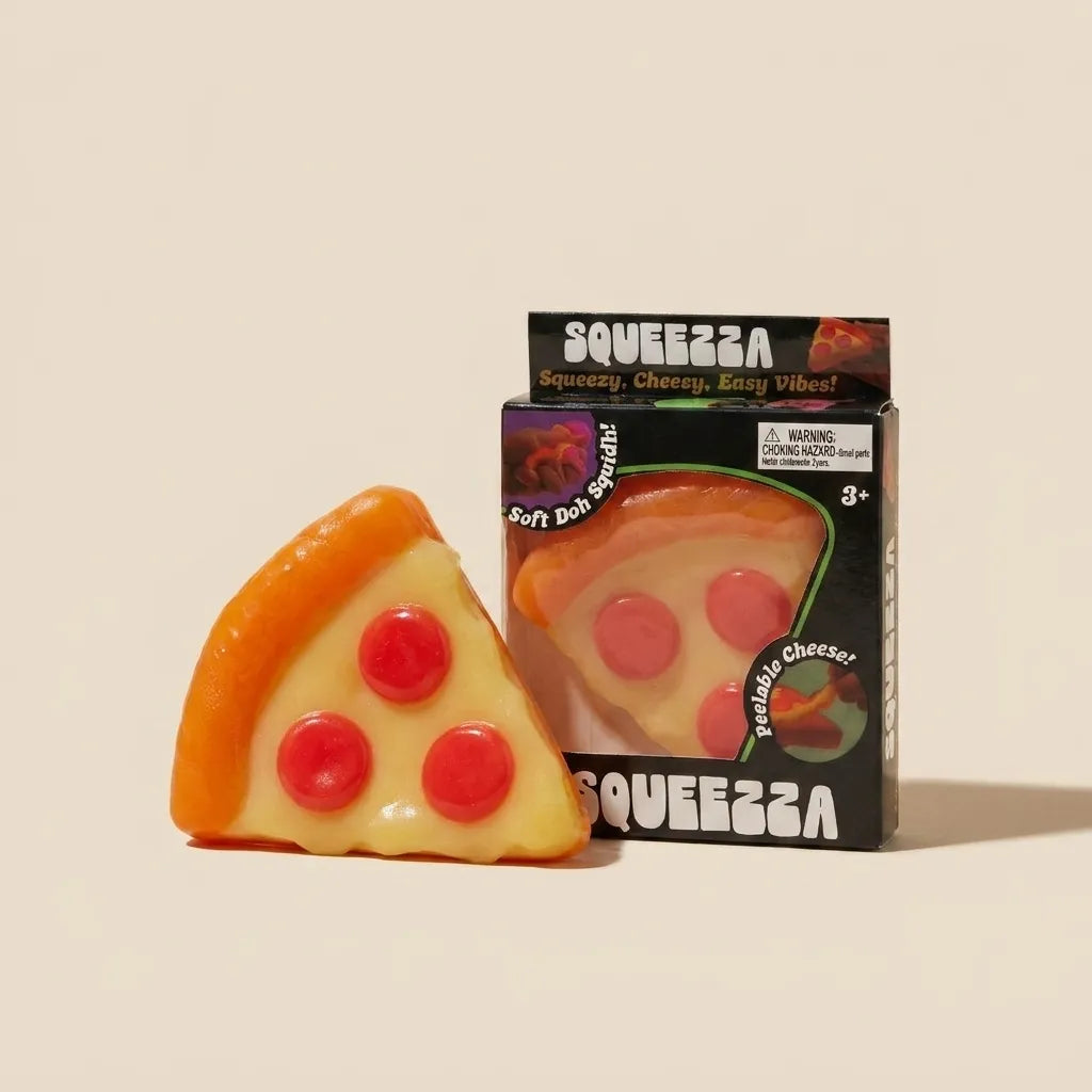 A slice-shaped squishy toy shaped like pizza, shown in front of its black retail box on a plain warm beige background. The toy has an orange crust, pale yellow cheese, and three red circular toppings.