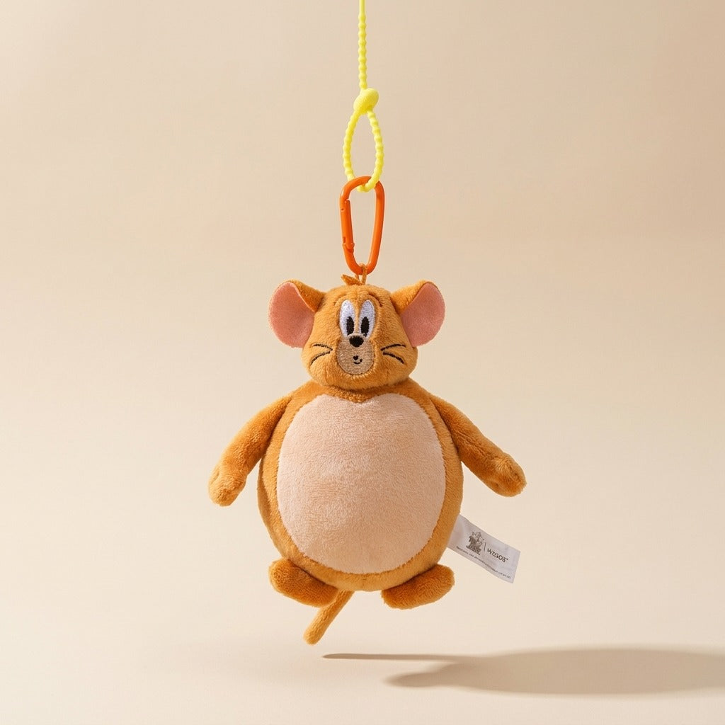 A plush Jerry Mouse hanging keychain or bag charm, featuring orange-brown fur, a cream belly, and a yellow hanging cord with an orange clip, shown against a solid beige background.