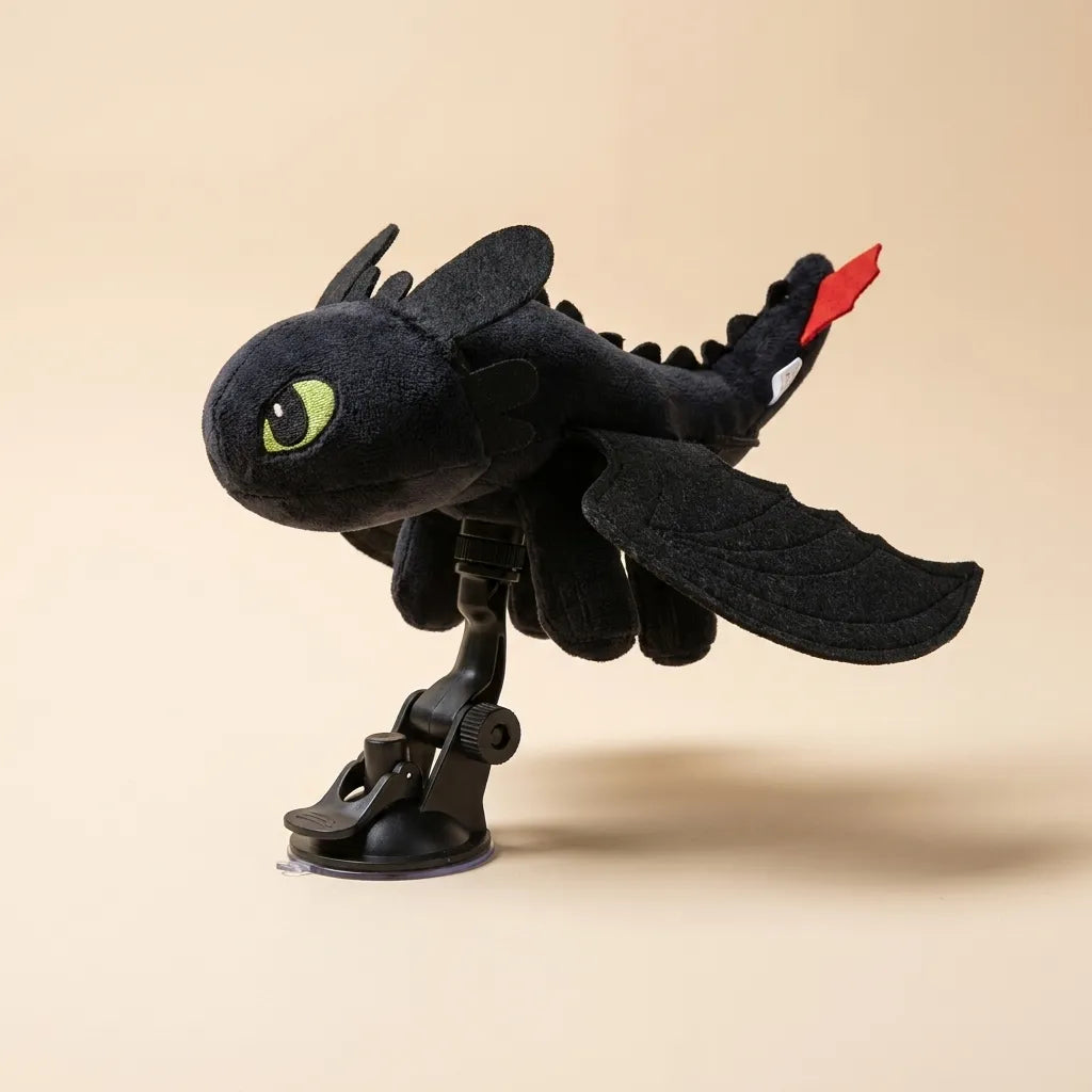 A black plush toy resembling Toothless from How to Your Dragon, mounted on a black suction-cup stand against a solid beige background.