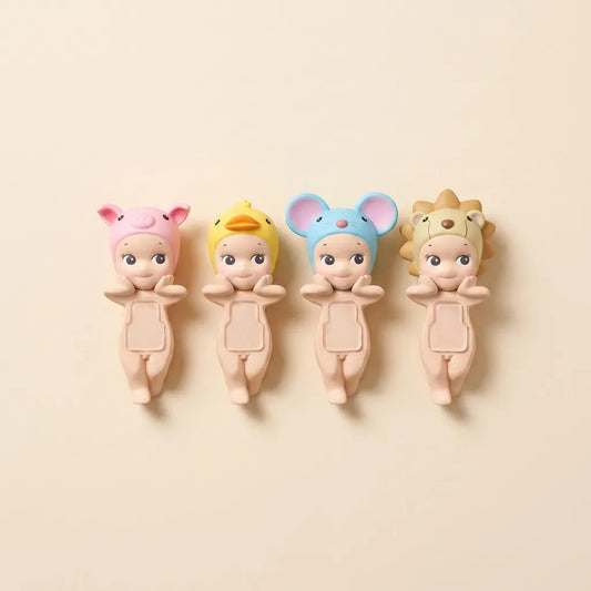 Four cute baby doll wall hooks shaped like animals, shown in pink pig, yellow duck, blue mouse, and beige lion designs on a warm beige background.