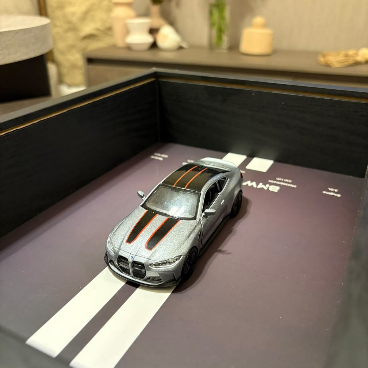 BMW M4 3D Framed Diecast Wall Art in a 32cm x 23cm black shadow box frame, featuring a grey 1:32 scale model car with open doors against an M-Power design background with performance stats.