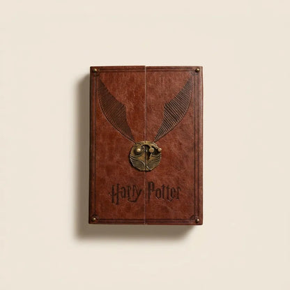 A brown faux-leather Harry Potter book-style box or journal cover with an embossed golden snitch design and the 'Harry Potter' title near the bottom, shown against a plain light beige background.