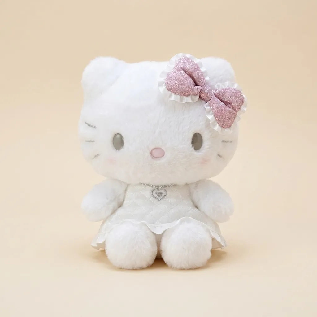 A white Hello Kitty plush toy wearing a white dress and a pink glittery bow with white ruffles, sitting against a solid beige background.
