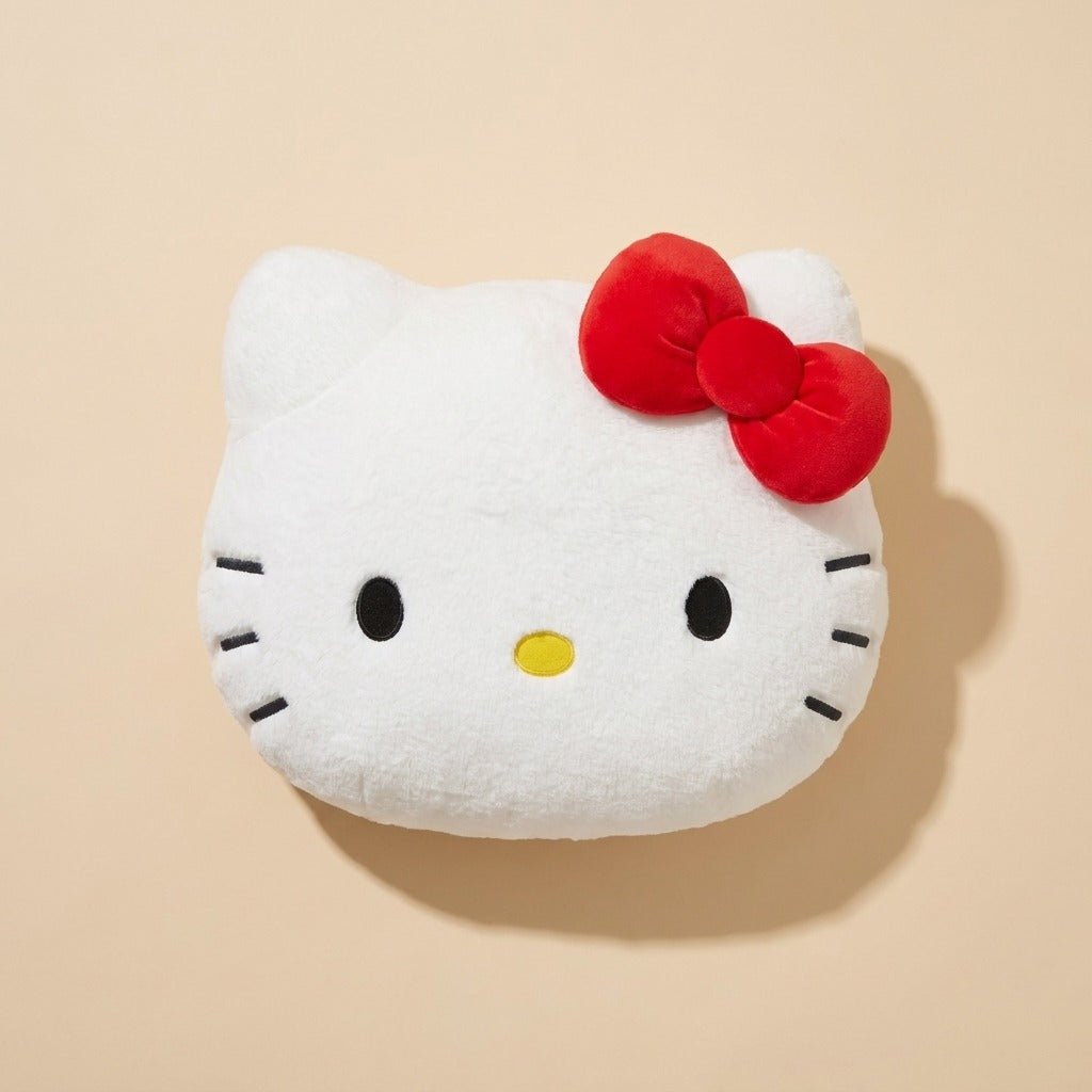 A white Hello Kitty plush cushion with a red bow and black facial details, shown against a solid beige background.