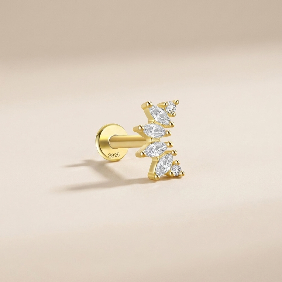 A single gold post piercing stud earring with marquise-cut clear gemstones, shown on a warm beige background.