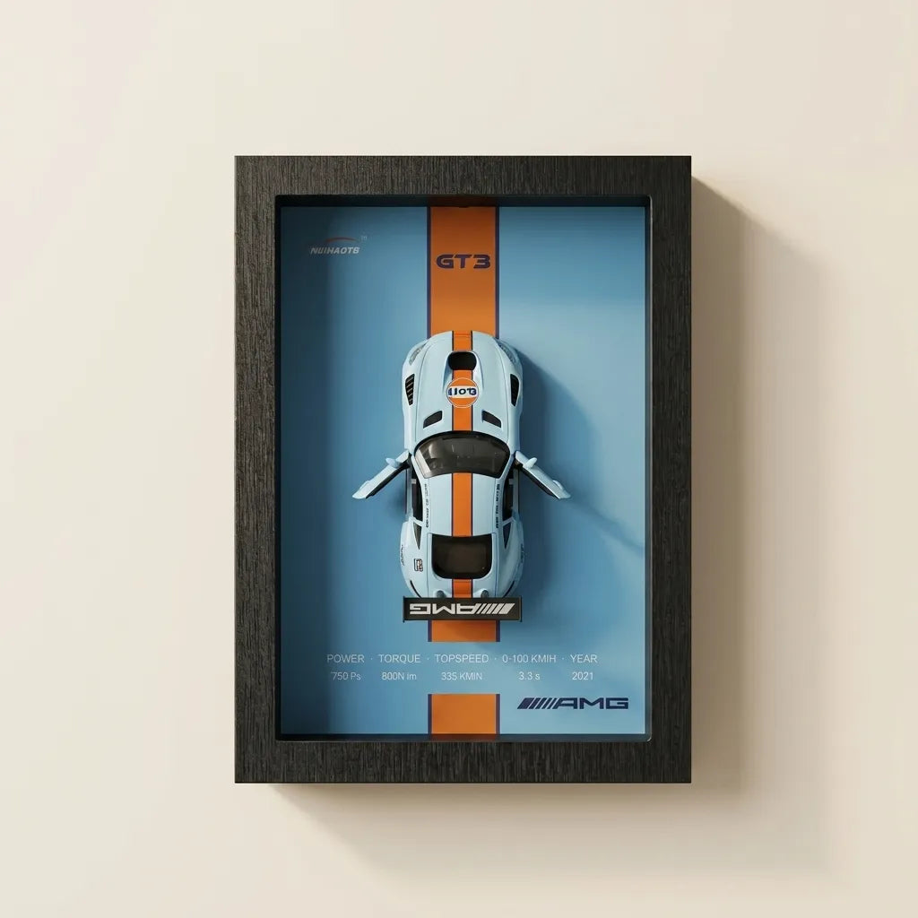 A framed AMG GT3 car poster featuring a white sports car with orange stripes on a blue background, enclosed in a dark wood frame and mounted on a light beige wall.