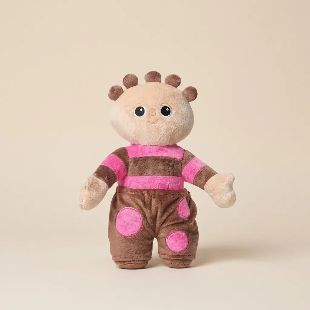 A plush toy doll with a beige face and hands, brown hair, and a pink-and-brown striped outfit with pink polka dots, standing against a plain beige background.